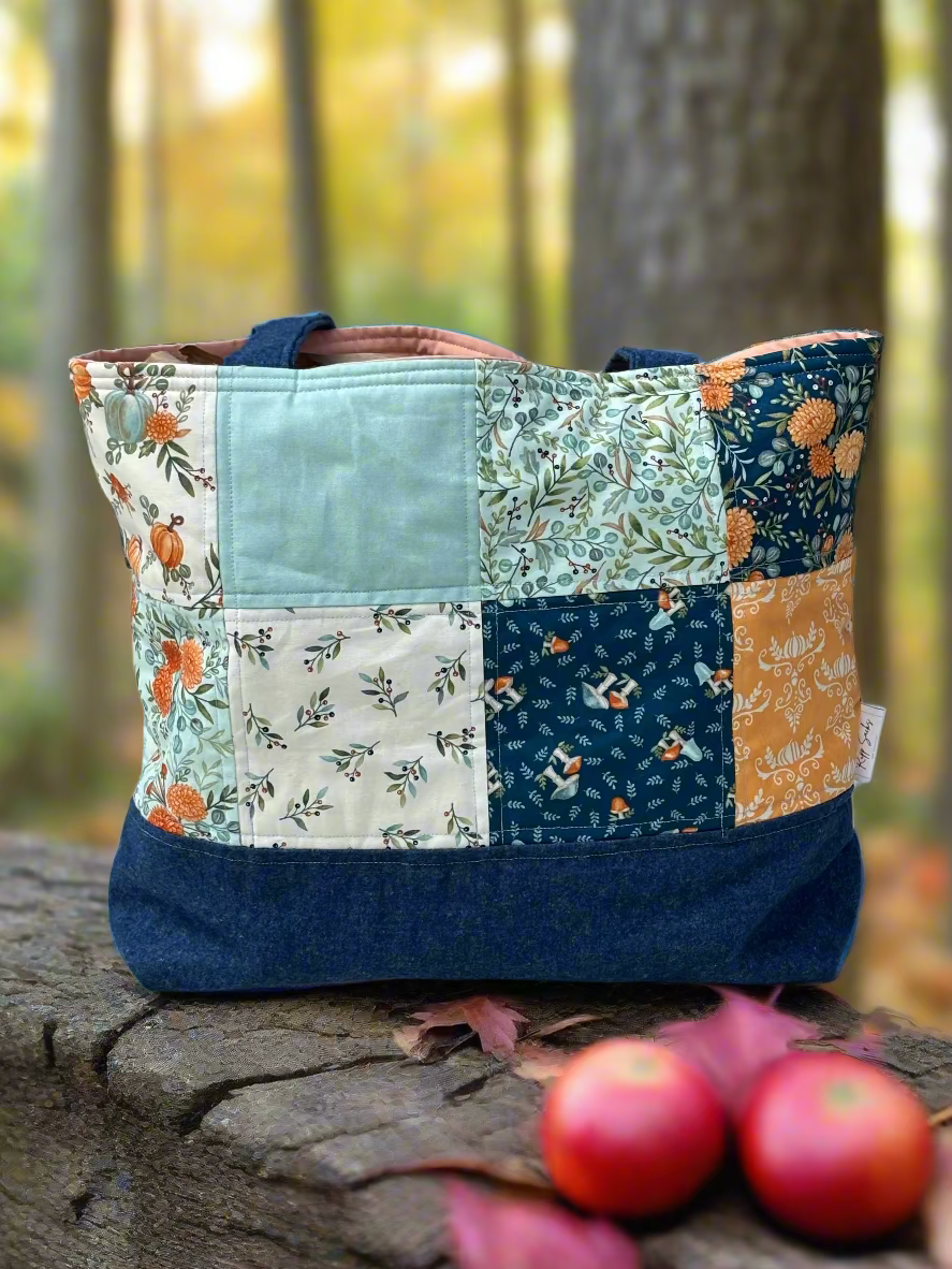 Patchwork tote bag with floral and nature-themed patterns on a wooden surface.
